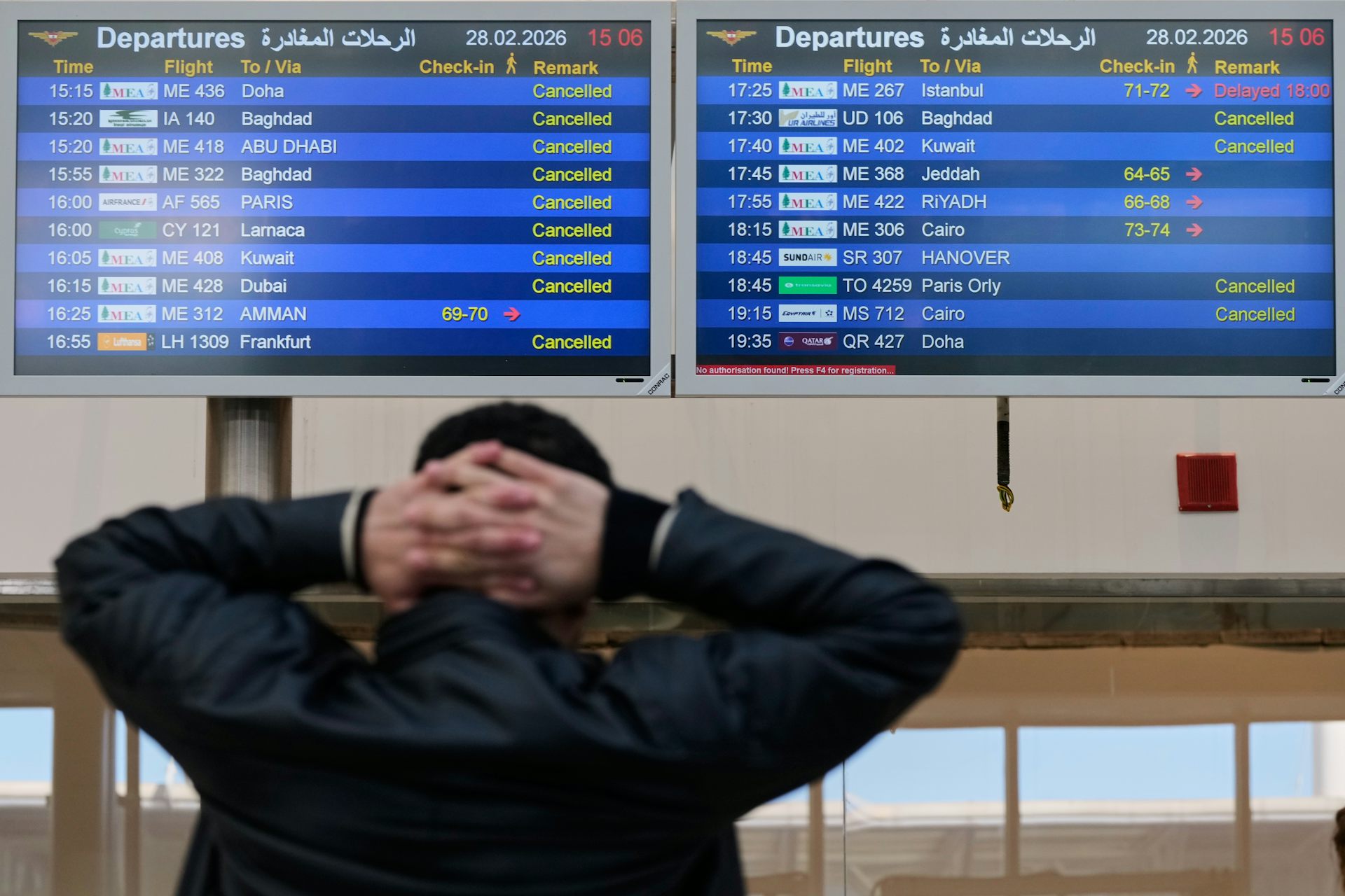 A traveller looks at an airport display showing most flights are cancelled 