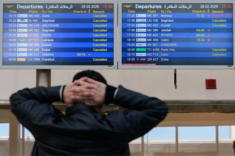 A traveller looks at an airport display showing most flights are cancelled