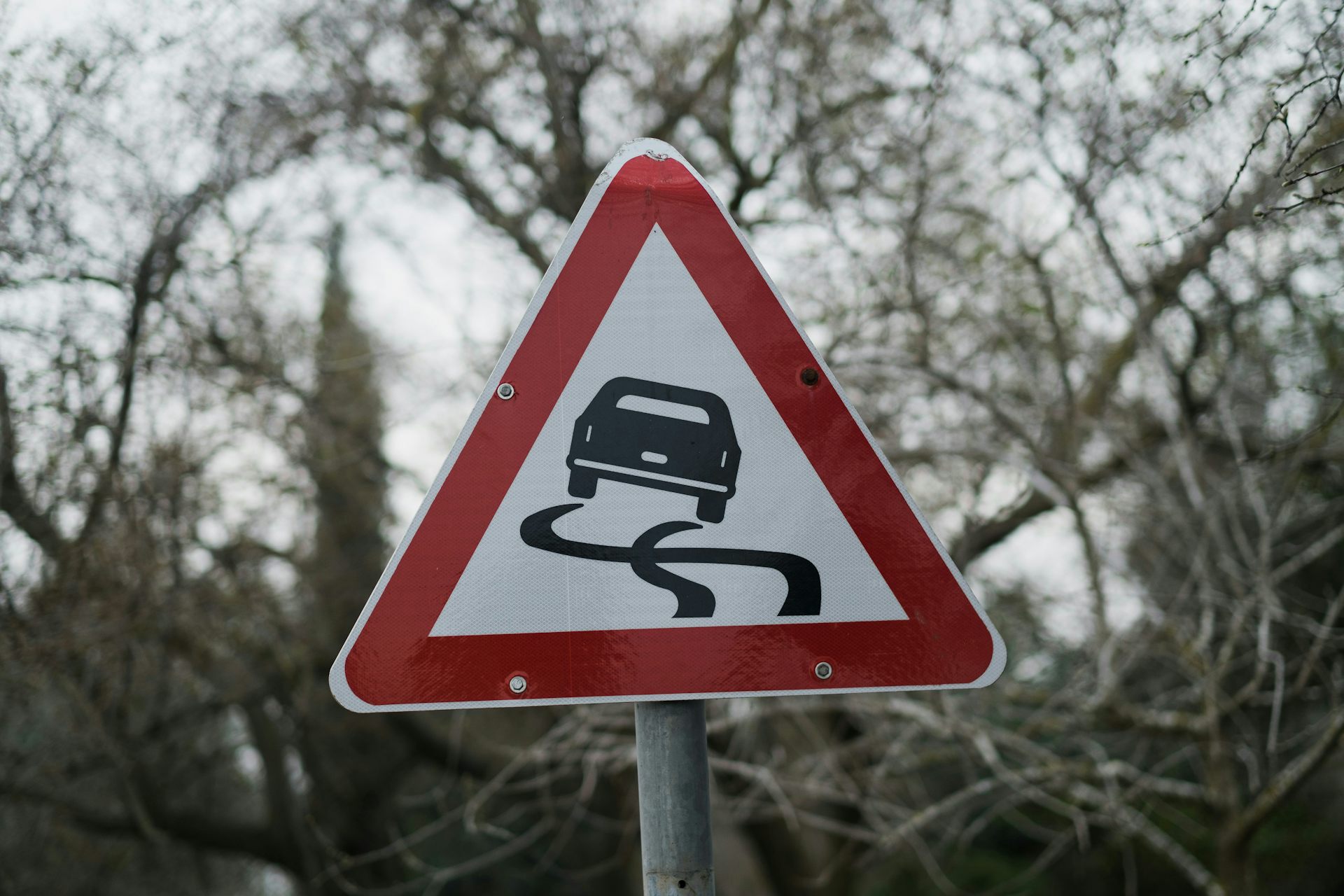 A triangular road sign with an icon of a skidding car