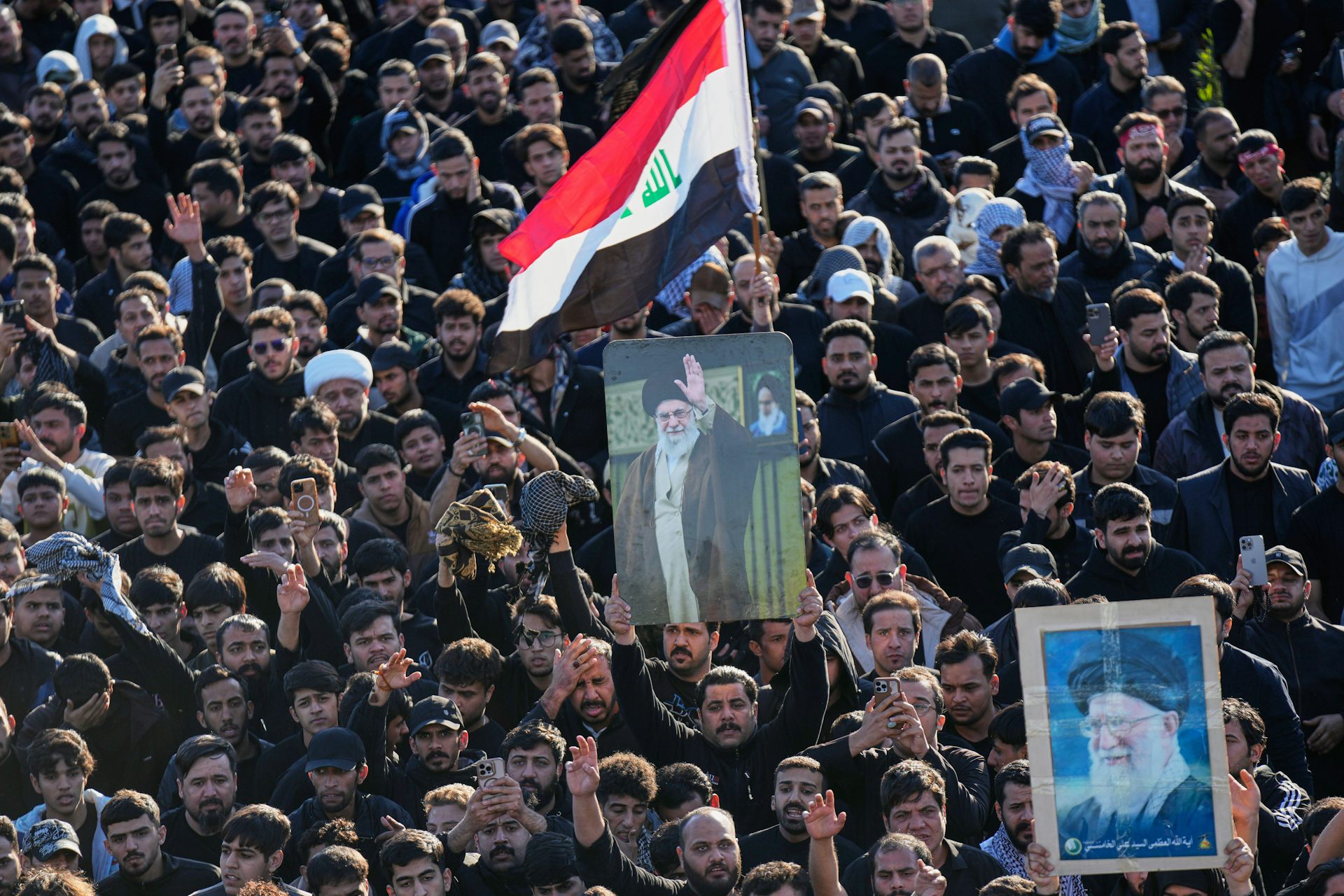 Thousands of Iranians mourn their supreme leader, Ayatollah Ali Khamenei, holdong up pictures and Iranian flags.