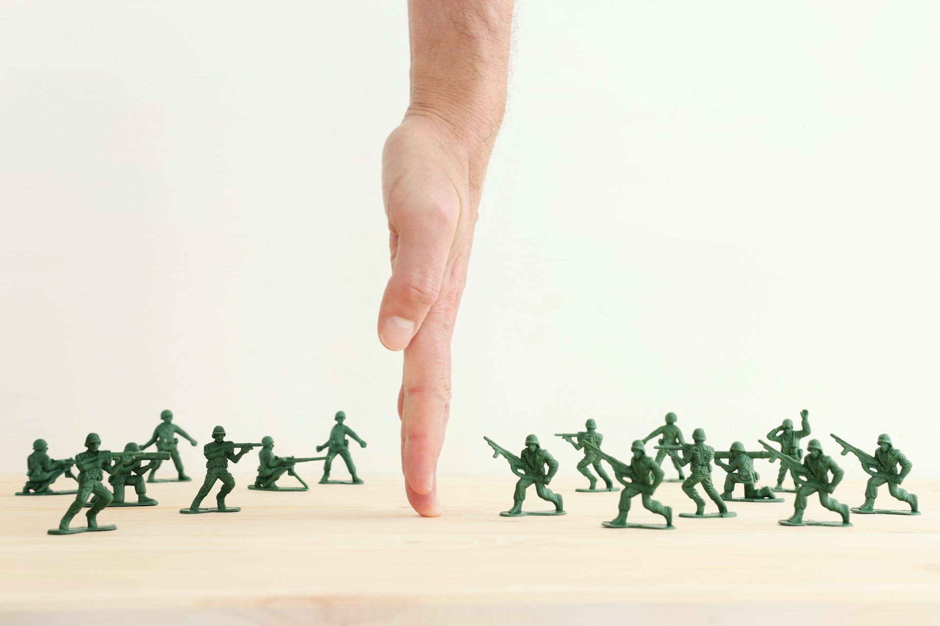 A hand separates toy soldiers on a table