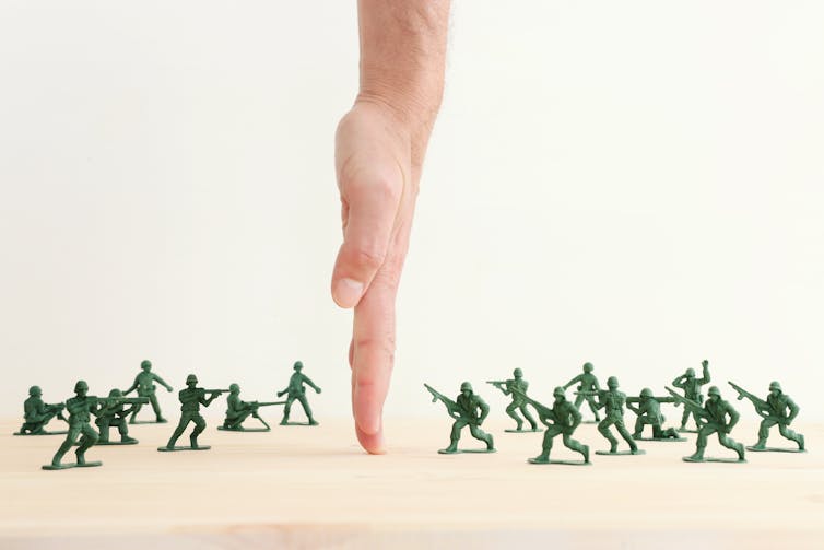 A hand separates toy soldiers on a table