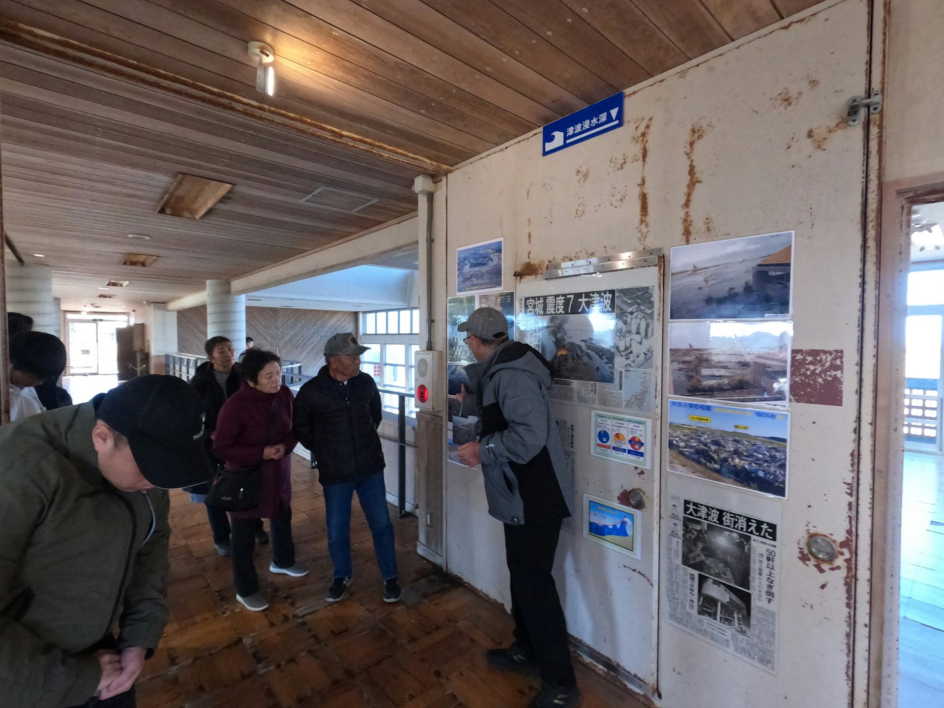 un hombre señala cuadros en la pared mientras habla con un grupo de personas.