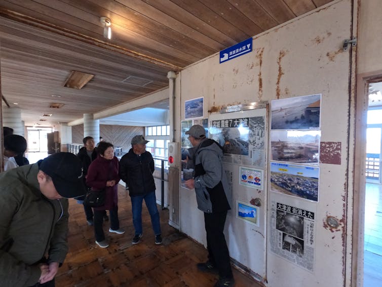 un hombre señala cuadros en la pared mientras habla con un grupo de personas.
