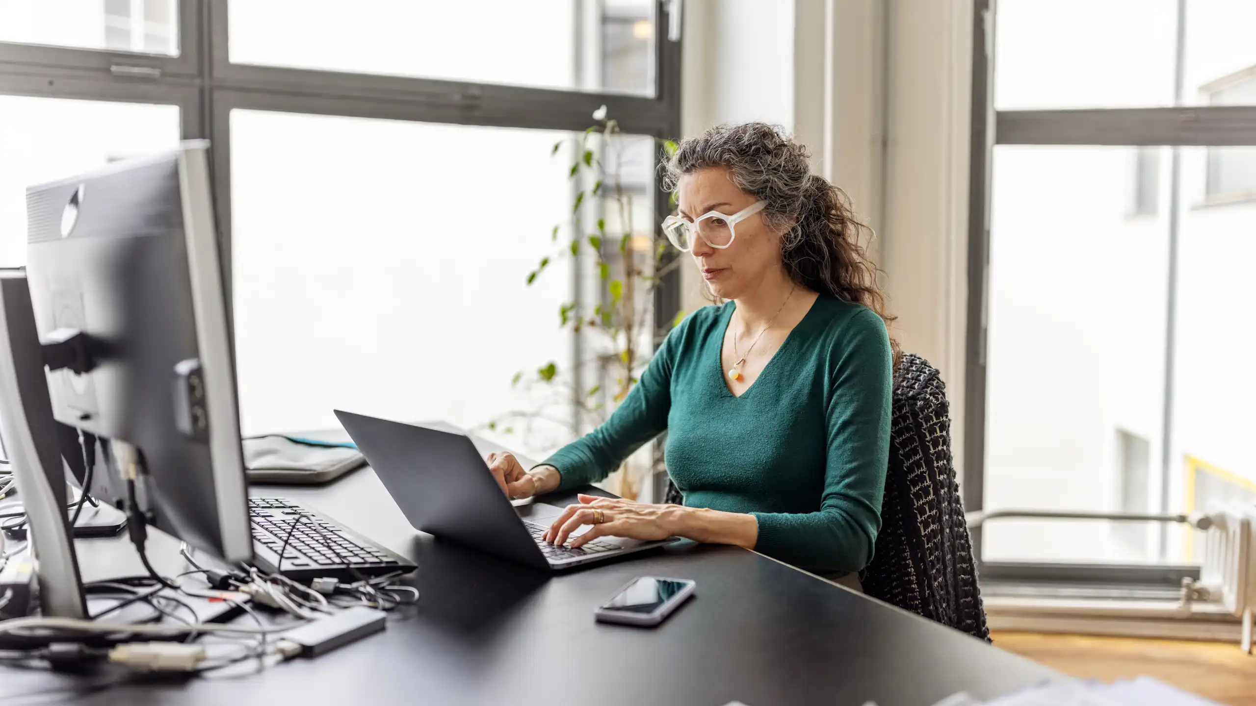 A woman works at a laptop in an office.