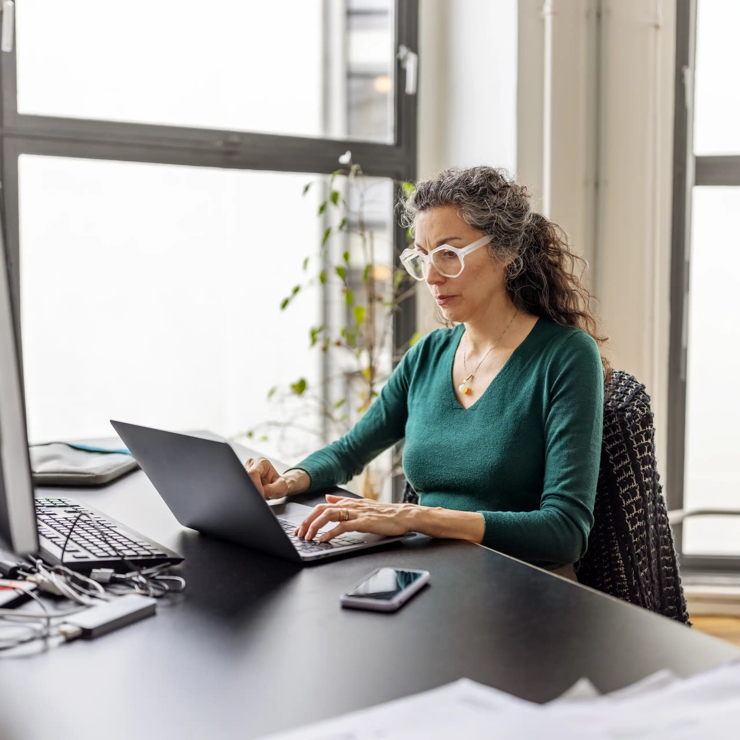 A woman works at a laptop in an office.