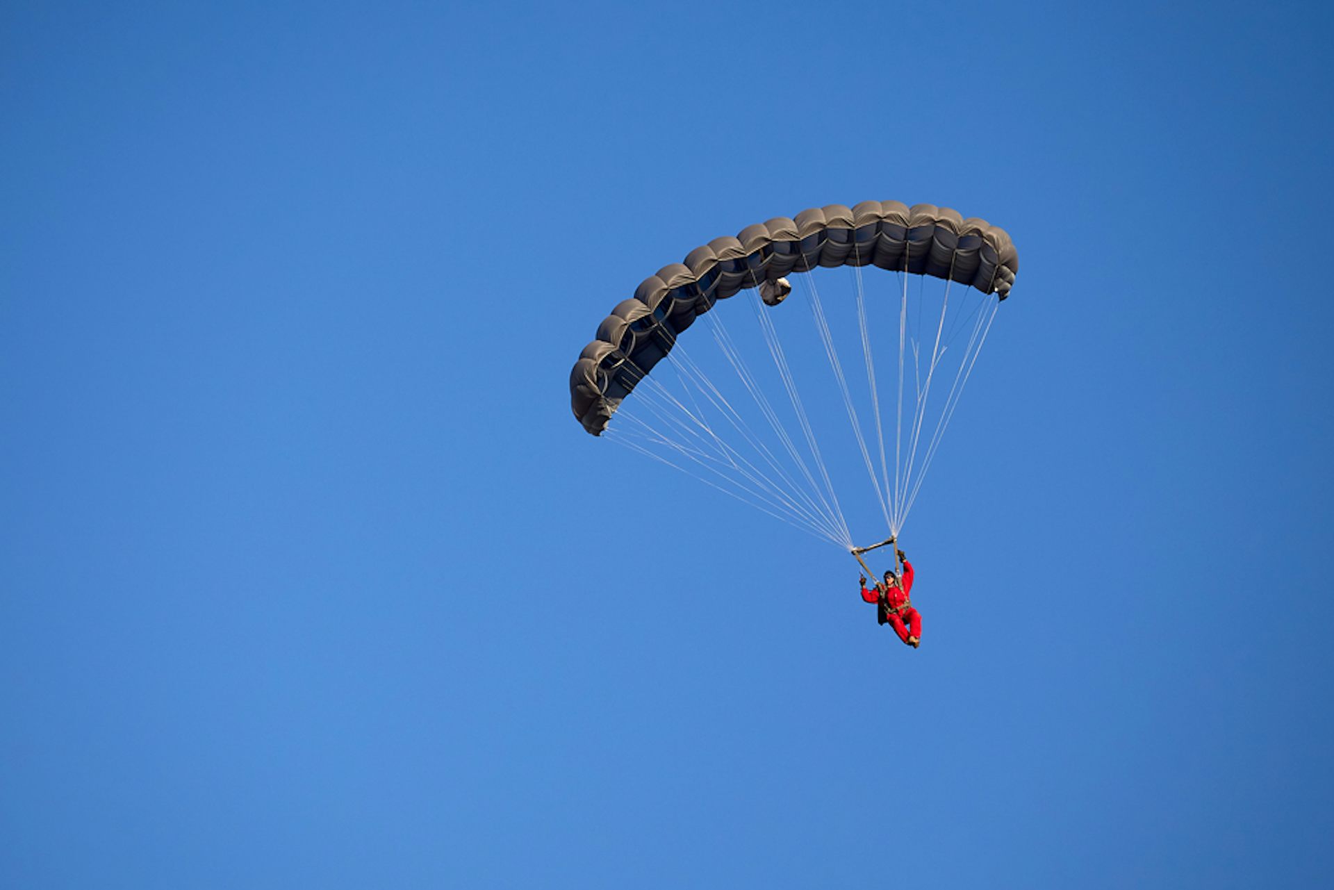 A pilot floating earthward, parachute deployed.
