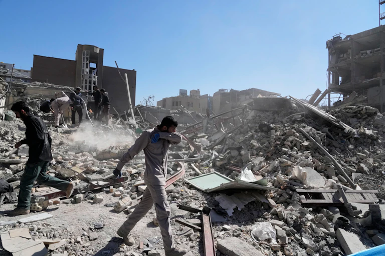 Several men walk amid the rubble of a building.
