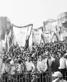 Hundreds of people hold banners in a city square.