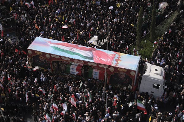 Hundreds of people surround a truck in a city square.