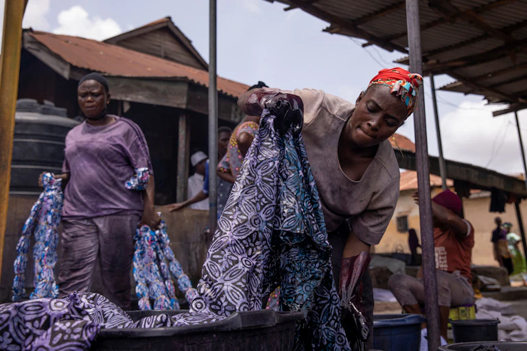 A woman holding a length of cloth over a bucket