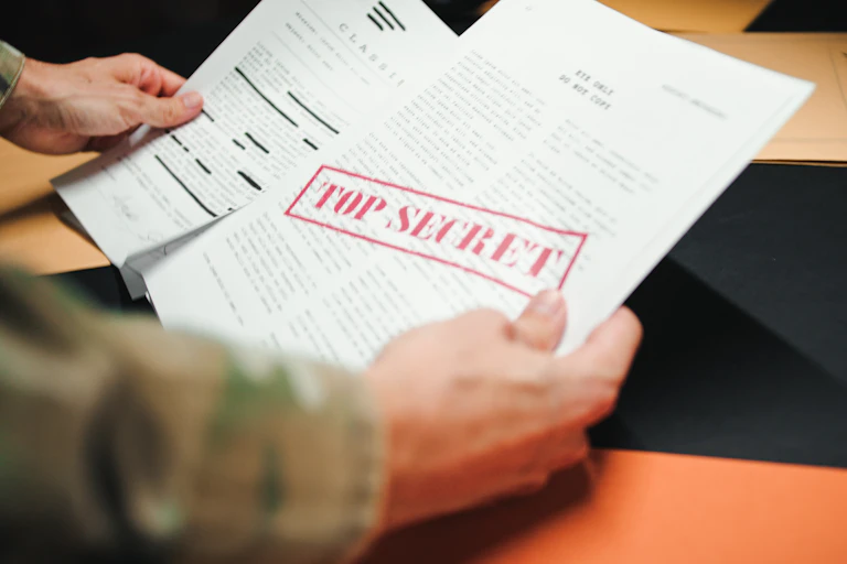 Unas manos sotienen documentos clasificados como "top secret".