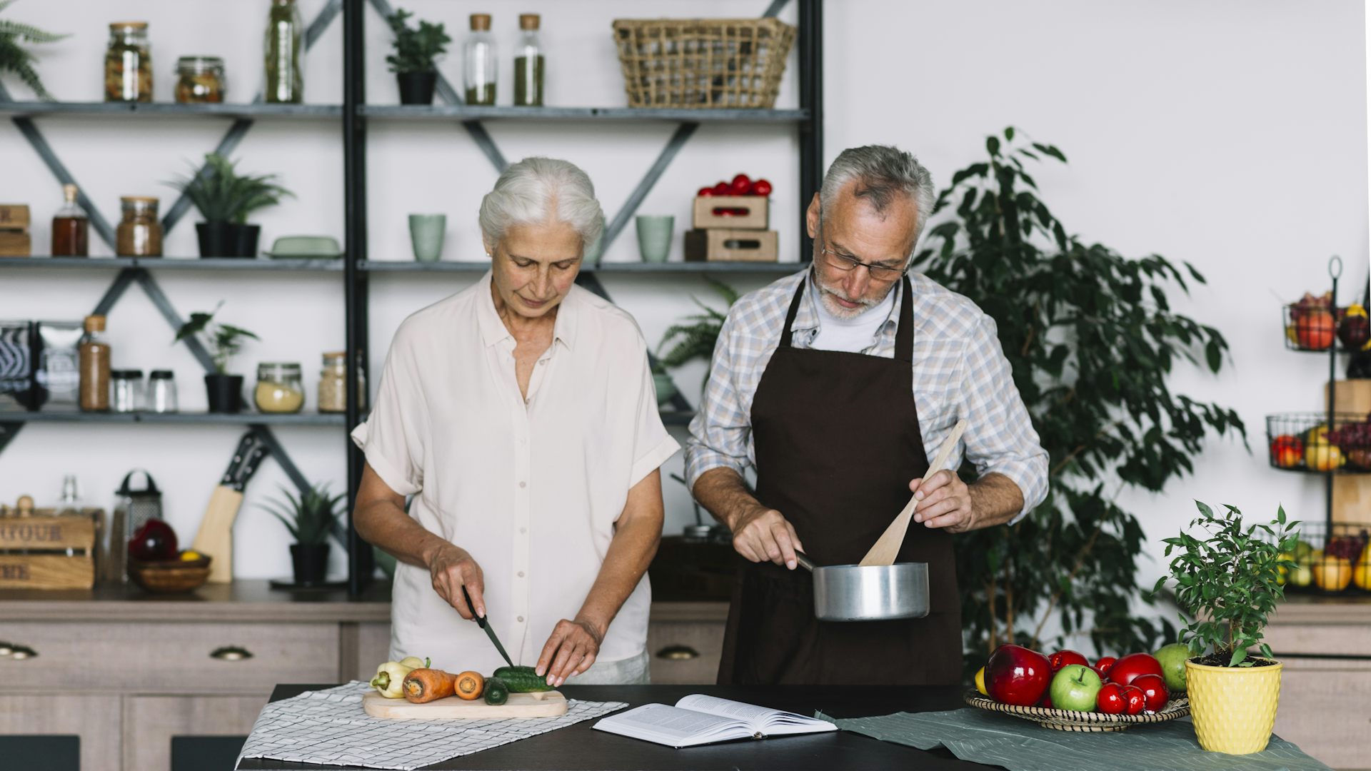 A man and a woman with grey hair preparing food