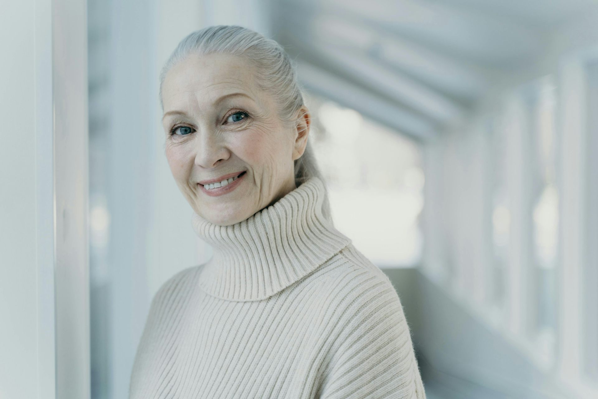 Mujer con el pelo gris recogido hacia atrás sonriendo