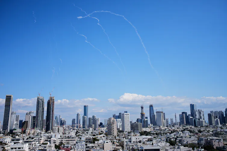 White streaks in a blue sky above a city.