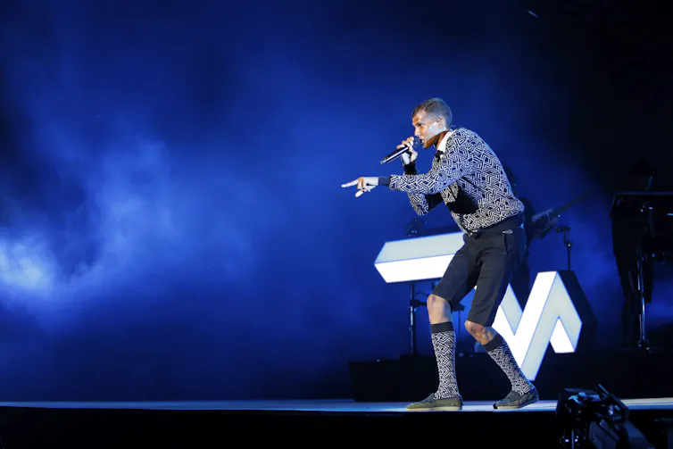 A musician on a stage holding a microphone and singing.