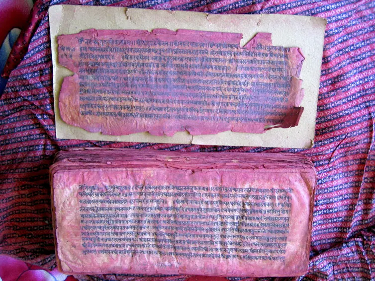Lo que significa un antiguo texto devocional para las mujeres de Nepal 1 Dos páginas de un libro manchadas con pintura roja.