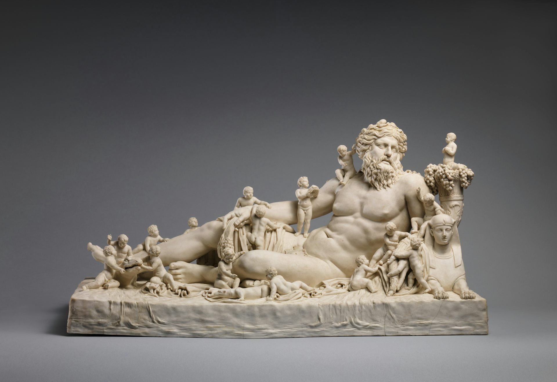 Porcelana representando um homem nu e barbudo reclinado, com crianças pequenas brincando ao seu redor.