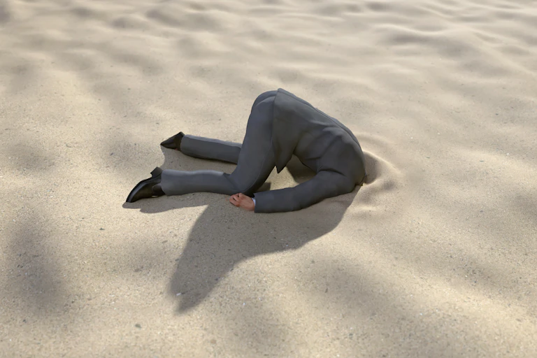 Homme faisant l'autruche dans le sable.