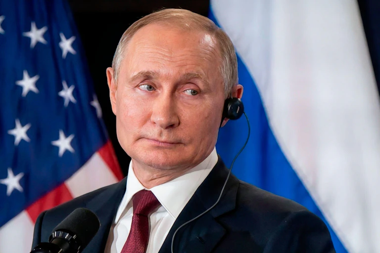 Vladimir Putin smiles as he listens to an earpiece.