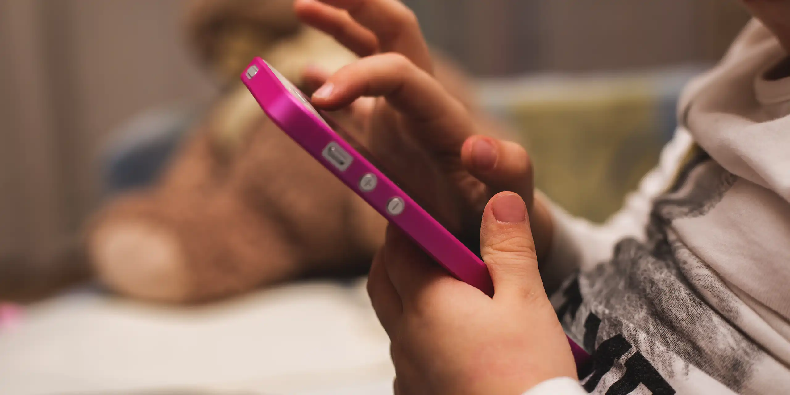 Child's hands holding pink mobile phone
