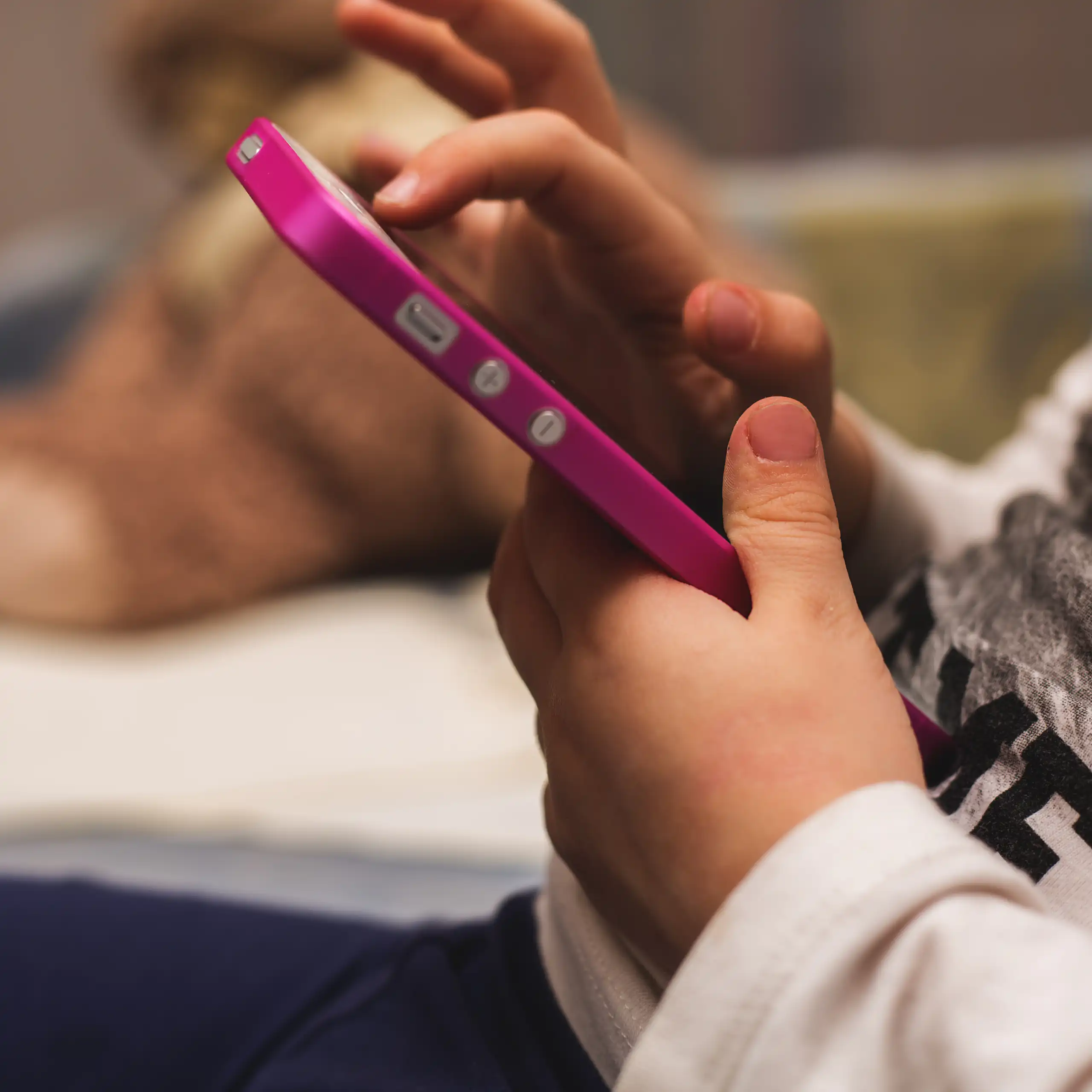 Child's hands holding pink mobile phone