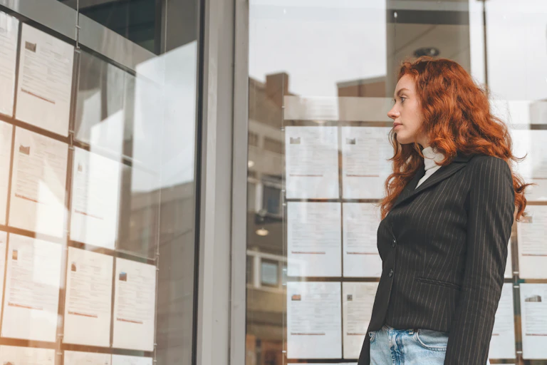 young woman looking at jobs listings in an agency window.
