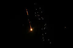 A missle flies through the air, lit up against the night sky