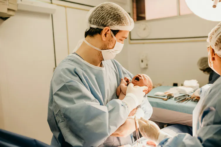 A doctor holds a newborn baby.