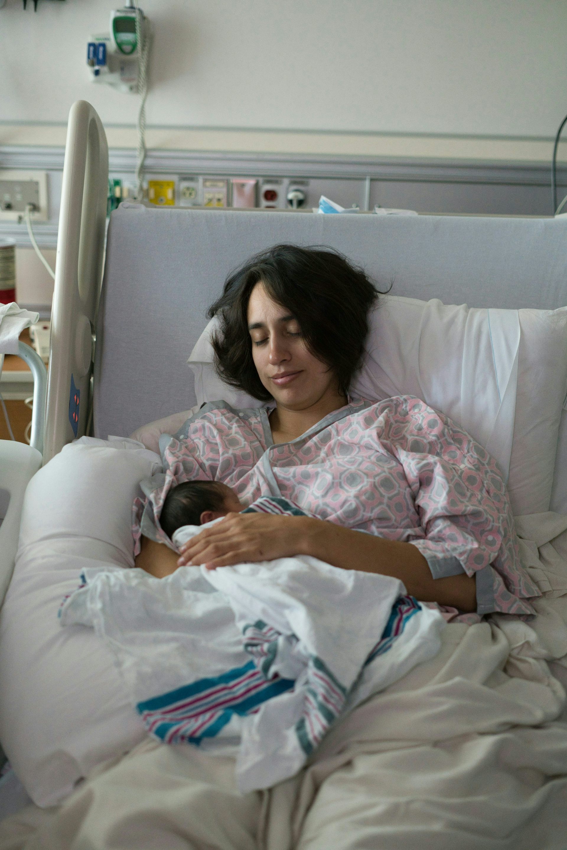 A mother holds her newborn in her hospital bed.