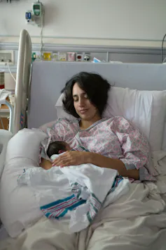 A mother holds her newborn in her hospital bed.