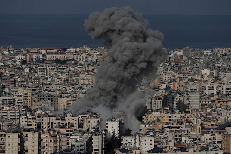 A massive plum of grey smoke rises up from a city
