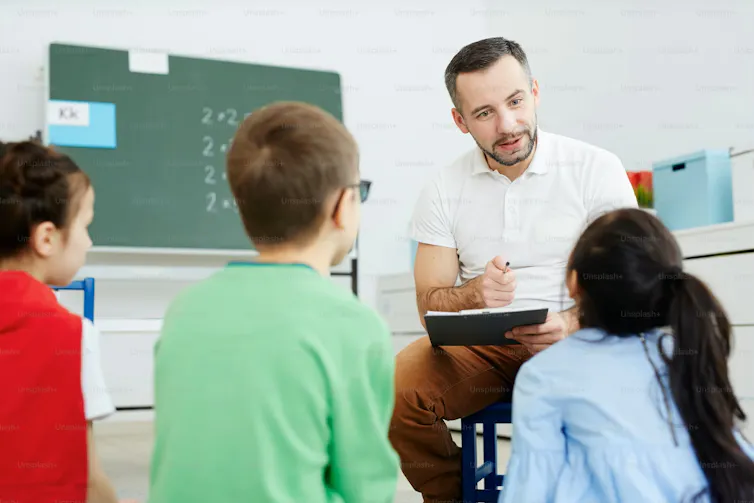 A teacher seen in dialogue with students.