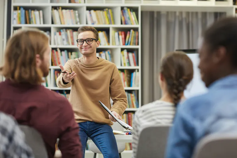 El hombre sonriendo frente al salón de clases.