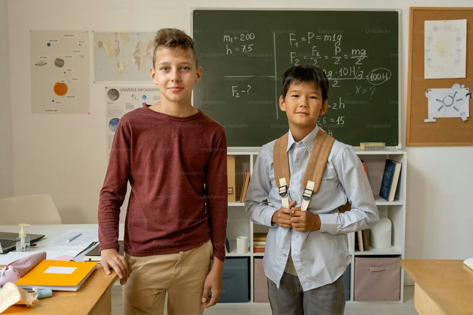 Dos niños parados en un salón de clases luciendo orgullosos.