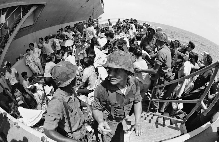 Hundreds of people stand on a ship.