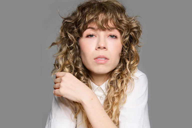 a curly-haired woman in a white top
