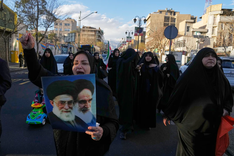 A woman, marching with others, holds pictures of Ayatollah Khomeini and Ayatollah Ali Khamenei.