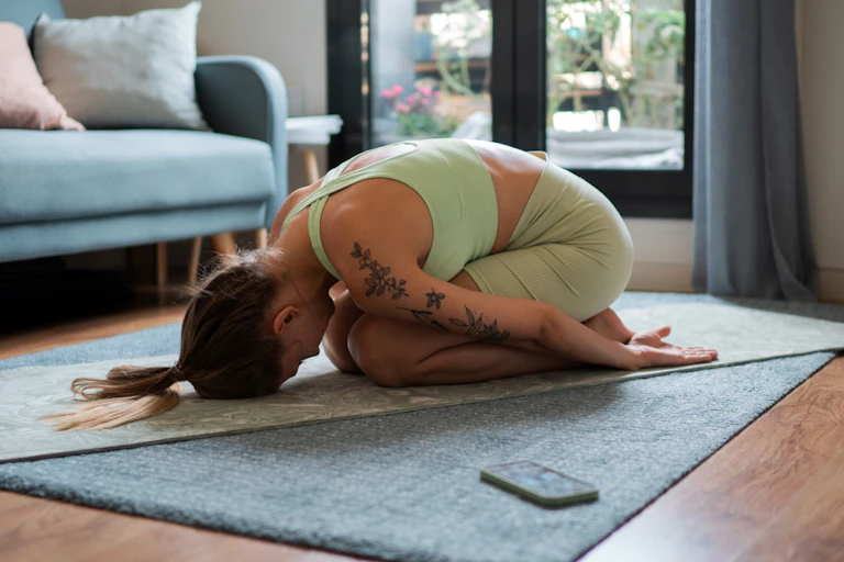 Woman holds yoga pose on a yoga mat.