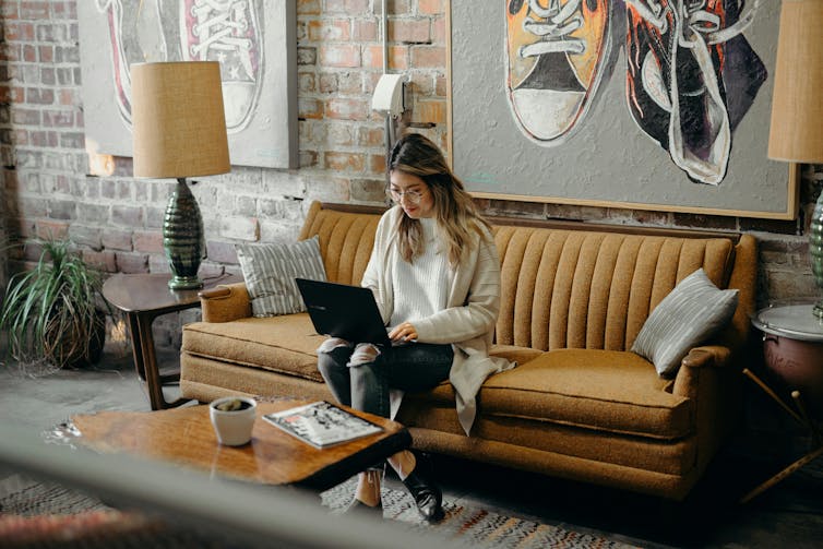 A woman sitting on a couch working on a laptop