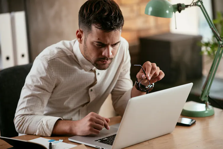 a man working on a laptop sitting at a desk