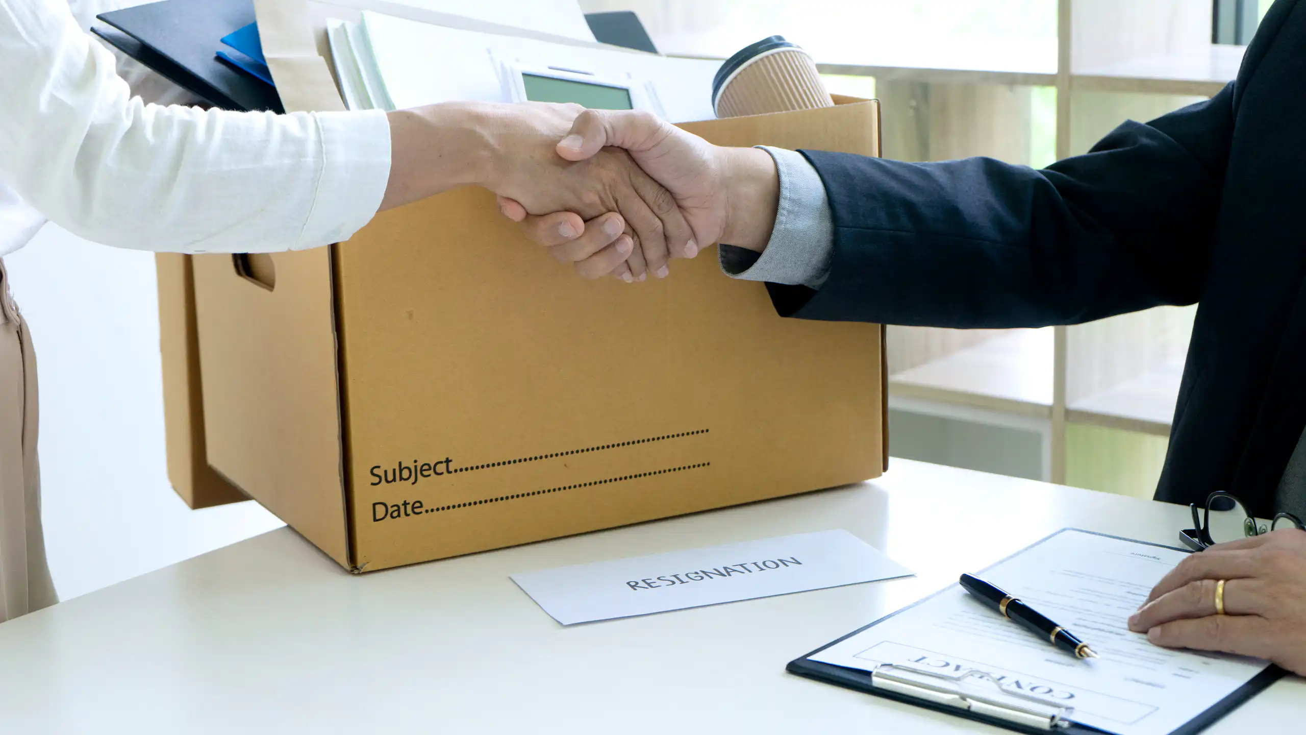 Personne partant de son travail avec un carton serrant la main de son patron.