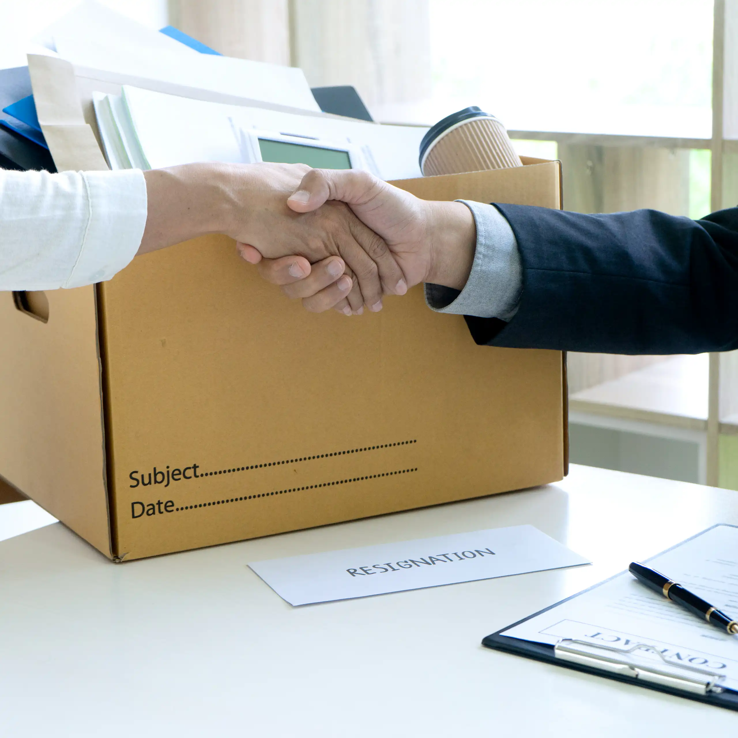 Personne partant de son travail avec un carton serrant la main de son patron.