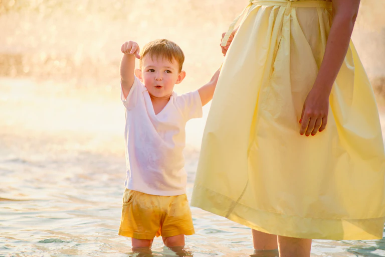 Un niño señala algo mientras da la mano a su madre.