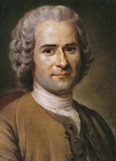 A man with dark eyebrows poses while wearing a gray wig and brown-yellow coat.