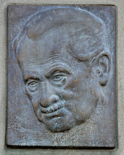 A stone relief etching of the face of a man with a mustache.