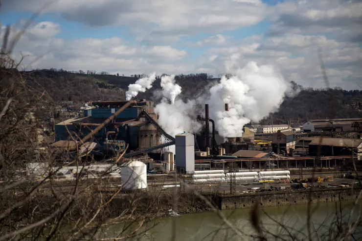 A riverside steel plant emits smoke from its smokestacks.