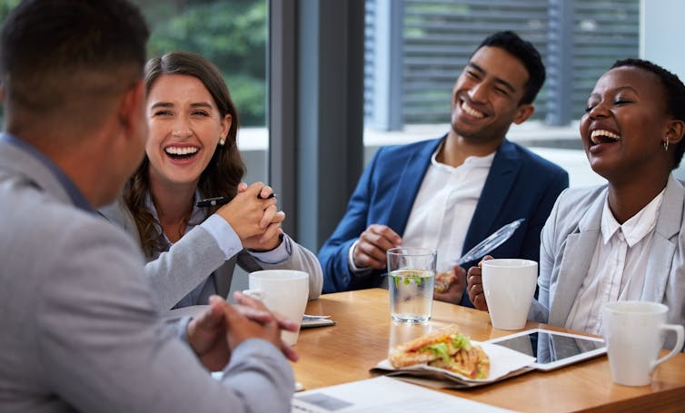group of four young professionals having a breakfast meeting over coffees.