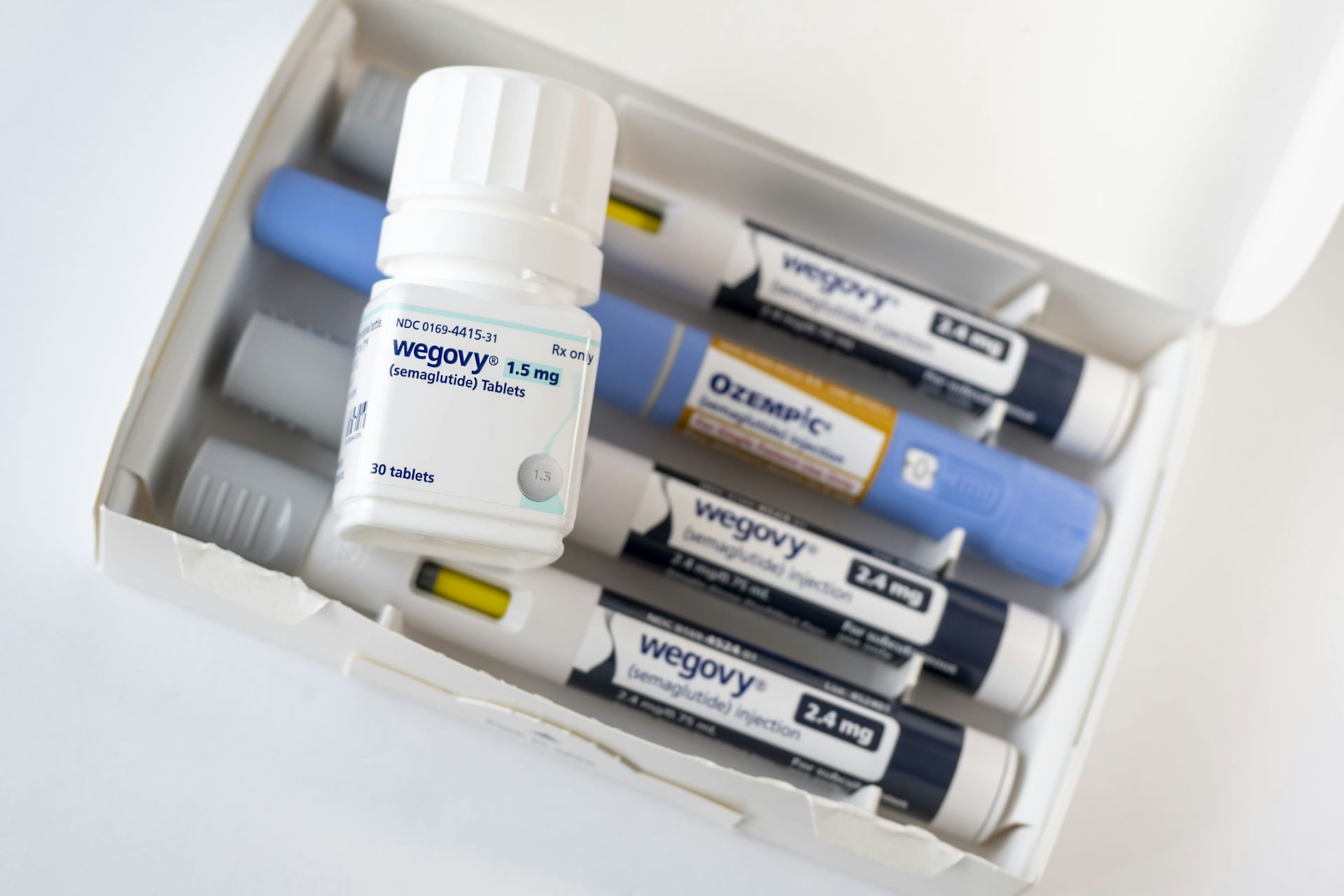 Frasco de comprimidos Wegovy em cima de uma embalagem de injetáveis Wegovy e Ozempic.