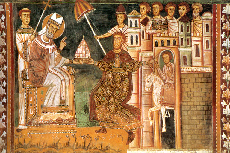 A faded mural in jewel tones shows a man in religious garb handing a crown to a man in richly colored robes outside city walls.